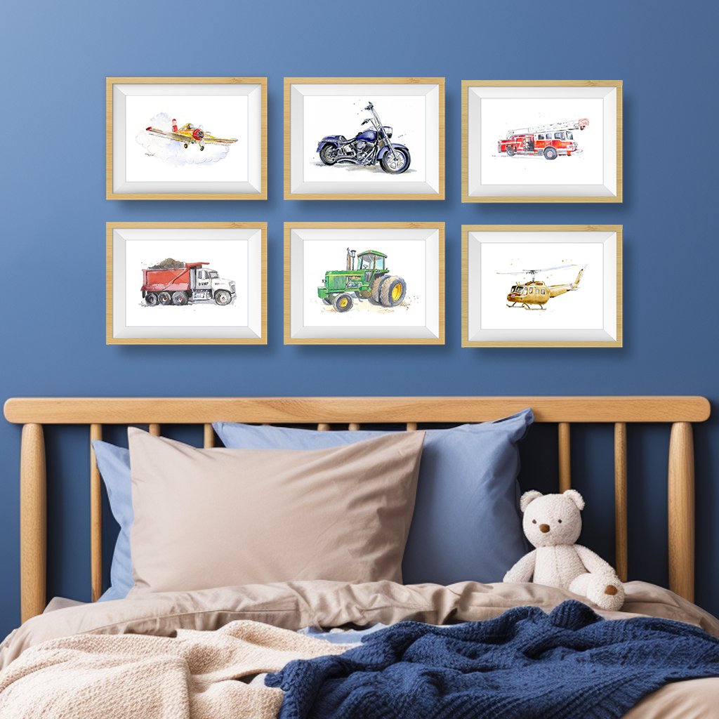 Set of 6 transportation watercolor prints hanging above a bed – featuring construction trucks, farm tractors, airplanes, motorcycles, sailboats, and helicopters in a classic nursery wall art display.