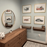 Thumbnail for Nursery Room interior with wooden dresser, round mirror, and framed rescue vehicle prints on the wall.