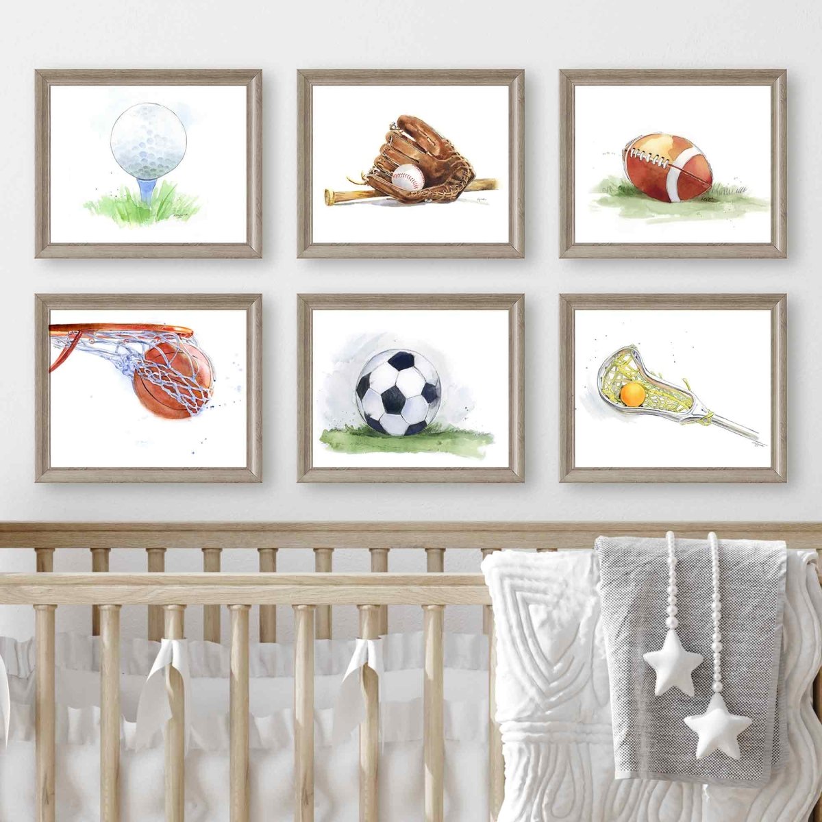 Framed illustrations of sports equipment on a wall above a crib.